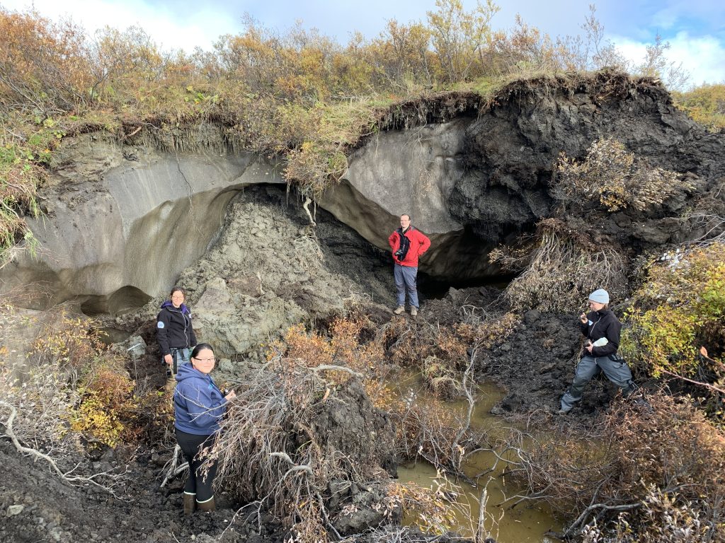 A research team from the Alfred Wegener Institute Helmholtz Centre for Polar and Marine Research posing in front of a small thaw slump near Kot