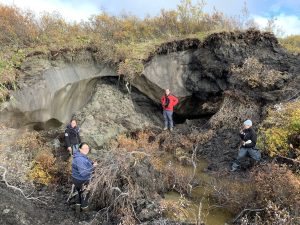 A research team from the Alfred Wegener Institute Helmholtz Centre for Polar and Marine Research posing in front of a small thaw slump near Kot