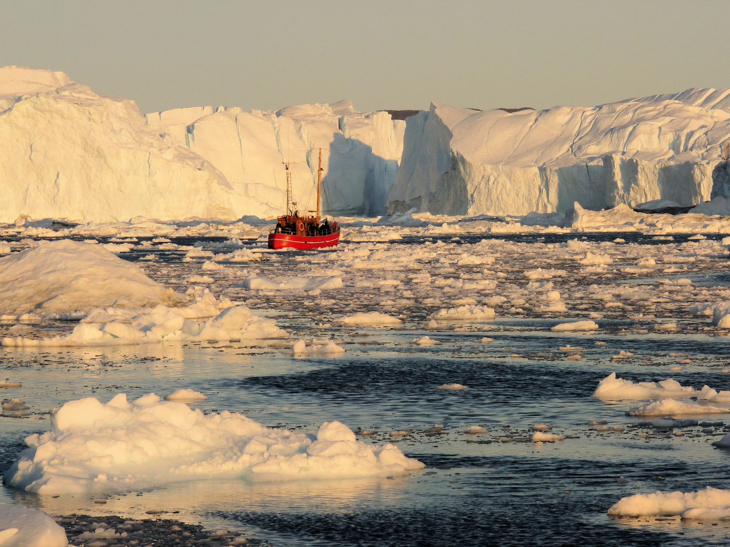 Small fishing boat in Ilulissat Icefjord, surrounded by icebergs that recently calved from Jakobshaven Isbrae, the worlds fastest flowing glacier.
Photographer: J Bamber